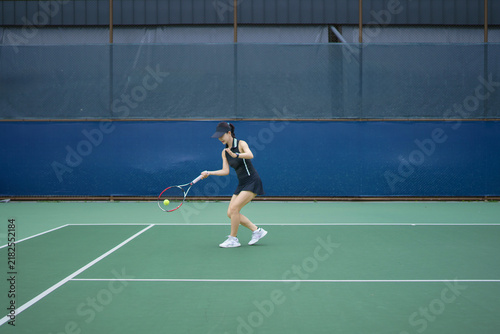 Fotografía Athletic Asian woman in tennis dress swings a forehand stroke on an outdoor clay