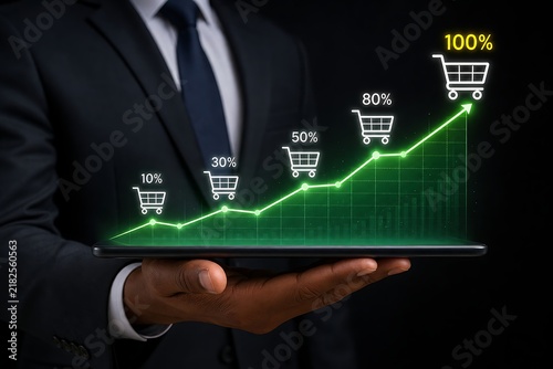 Businessman holding a tablet with a glowing green growth chart and shopping cart icons on it