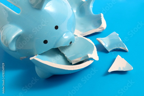 On a blue background lies a broken blue piggy bank.