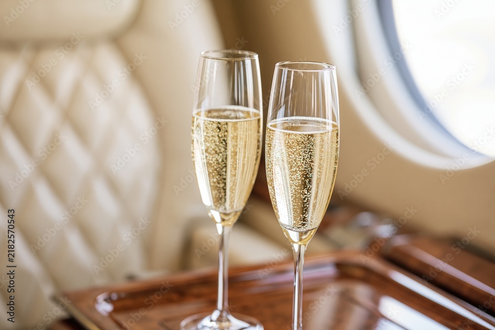 Obraz premium The Champagne Glasses on a Tray in a Luxurious Airplane Cabin