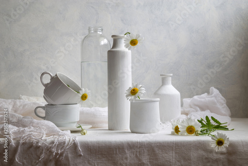 Konstfotografi Contemporary still life with daisies and white dishes on a light background