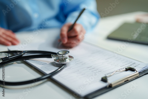 Obraz na plátně Healthcare administrator reviewing an insurance policy schedule with a stethosco