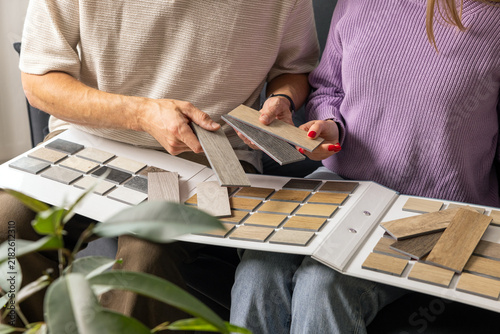 Couple choosing flooring and furniture materials from wood samples for home renovation. Interior design