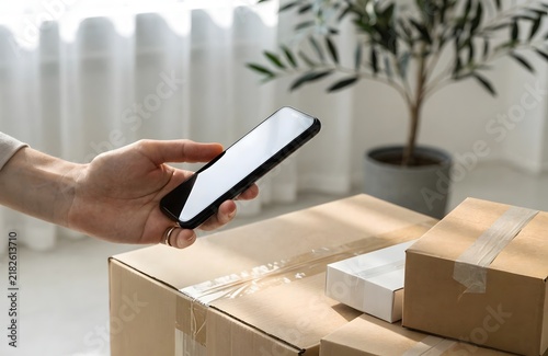 Hand holding smartphone scanning parcel box for delivery tracking or online shopping order