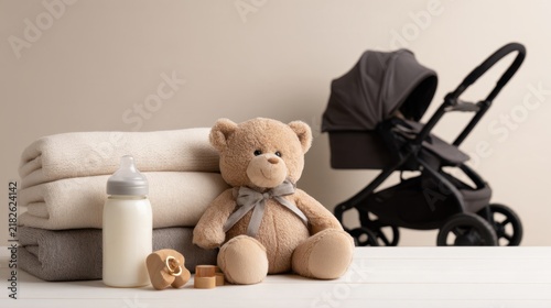 A cozy display of baby essentials including blankets, a teddy bear, a bottle, and a stroller