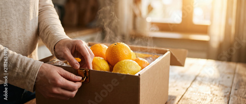 Warm hand holding fresh citrus grocery box for cold chain logistics