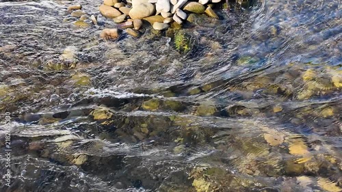The flow of a clear, clean mountain river in the shallows, natural background
