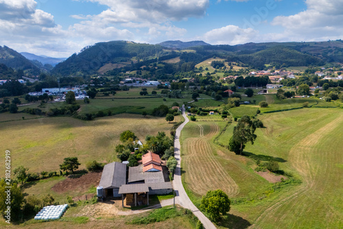Canvas Print Panoramic aerial view of a rural farmstead alongside a narrow road with green fi