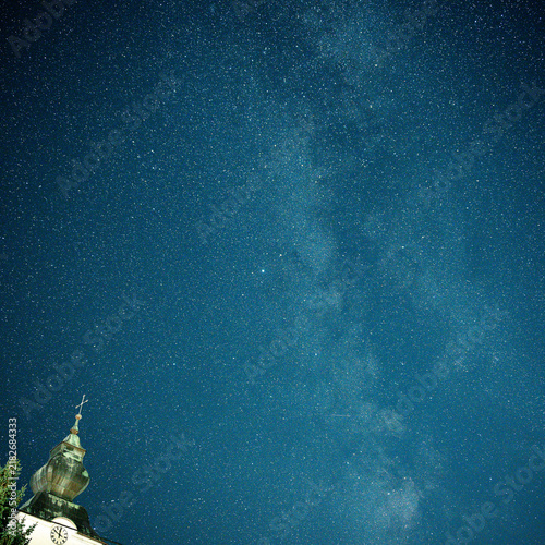 Foto Milky Way and countless stars above an illuminated historic church tower with an onion dome, combining astronomy, night sky and traditional European architecture
