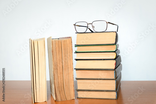 Cuadro en lienzo Stack of old hardcover books on a wooden table with eyeglasses on top