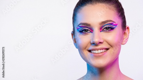 Portrait of a beautiful woman with colorful creative eye makeup makeup with against white background background neon lighting