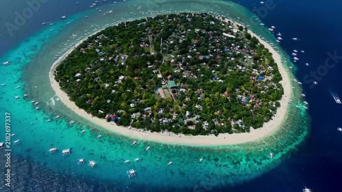 Aerial view of tropical island surrounded by turquoise water and coral reef