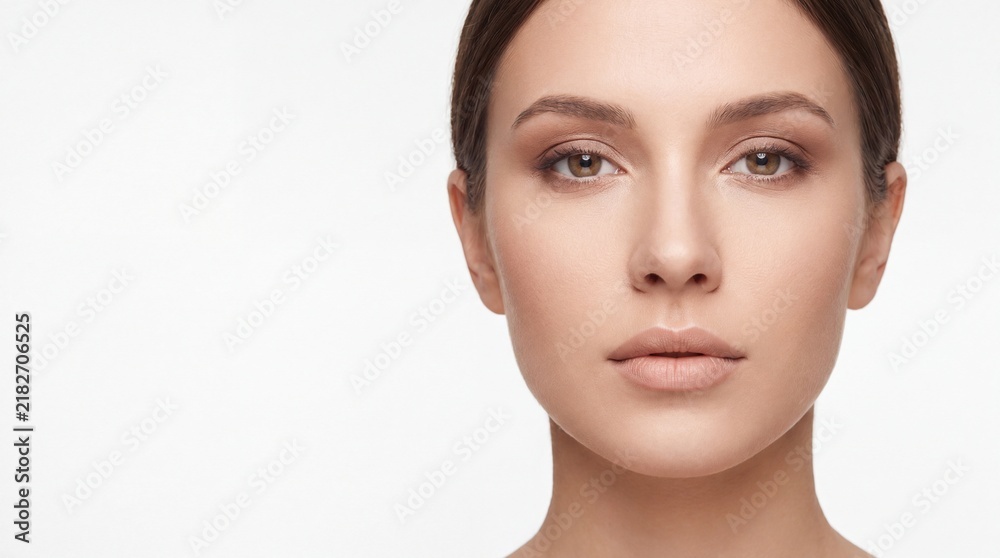 Fototapeta premium Portrait of a young woman with natural makeup looking at the camera against a white background with facing forward