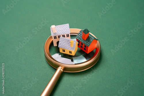 Houses under magnifying glass, real estate inspection and analysis concept. Property valuation, housing research and investment decisions depend on location, market prices and development potential.