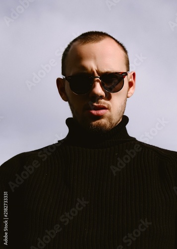 Bild auf Leinwand Portrait of a confident brutal man in black turtleneck and sunglasses outdoors i