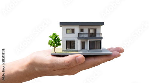 A person holding a small miniature model of a modern house in their hand