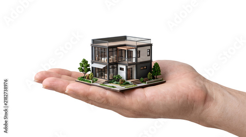 A miniature modern house model held in the palm of a person hand isolated