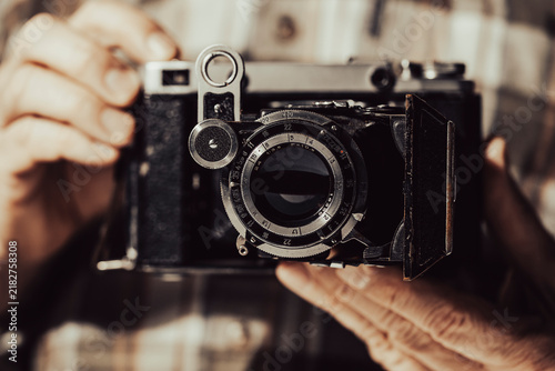 Fotografie Closeup of hands holding vintage folding camera