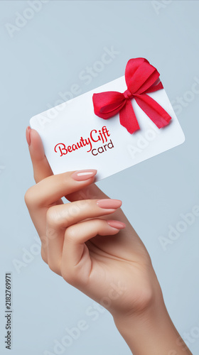 Woman holding a gift card for a beauty salon, representing a voucher for beauty treatments, self-care, cosmetics, shopping and a thoughtful gift for a special occasion.