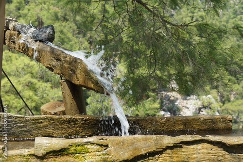 Canvastavla View of water from mountain spring flows down trough into old wooden tank