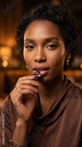 Beautiful Black woman enjoying a gourmet chocolate truffle in a luxurious setting with elegant warm lighting portrait