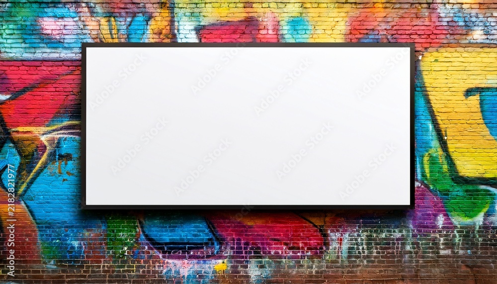 Fototapeta premium blank white billboard on a brick wall covered in colorful graffiti