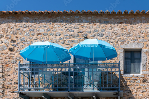 Two blue beach umbrellas on stone house balcony
