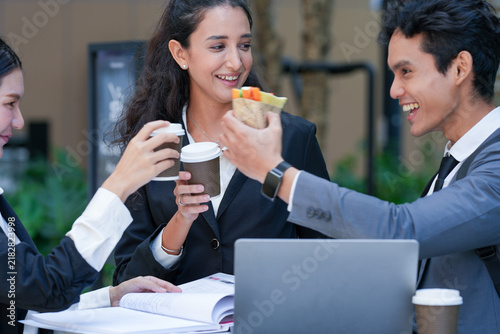 Foto A confident multicultural business trio sharing a laptop screen across a cafe ta