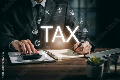 Accountant calculating taxes with digital financial icons and documents on office desk