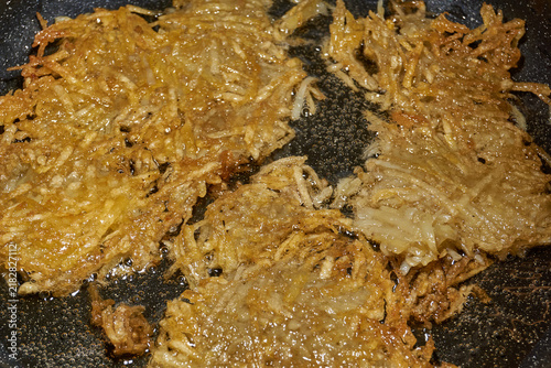 фотографія Large grated potato fritter cooking in a frying pan