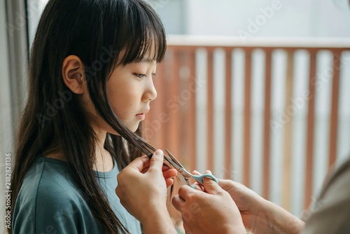 Mother cutting her daughter hair at home with scissors during a quiet family lifestyle day