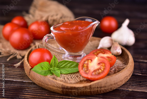 Bild auf Leinwand Tomato sauce in a sauce pot on a wooden tray. Close-up.