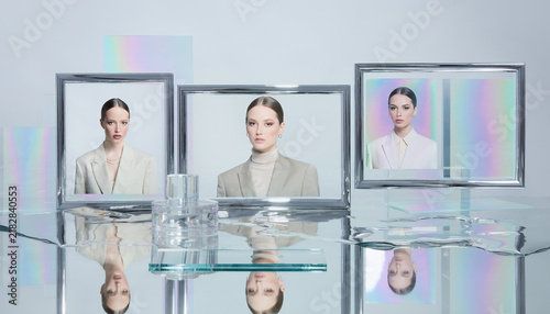 Ultra clean futuristic editorial fashion photograph of a model wearing a metallic holographic chrome trench coat, visor, and boots with matching silver handbag