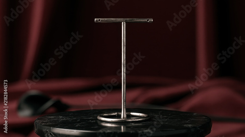 Vintage metal earring display stand on black marble against dark burgundy velvet with dramatic lighting and elegant gothic luxury aesthetic