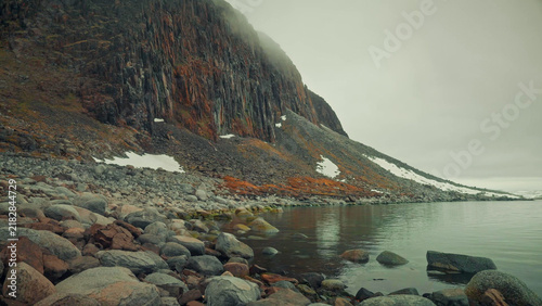 Konstfotografi Red columnar cliffs and boulder shore under arctic fog