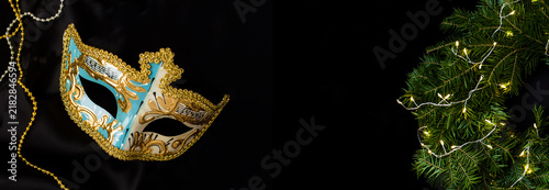 Christmas wreath and carnival mask on a black background. Copy space. Top view.