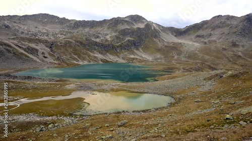 Turquoise and pale green mountain lakes beneath rugged rocky peaks in the Swiss Alps during early autumn.