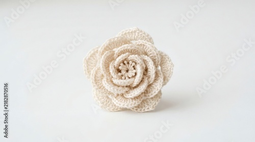 A delicate crocheted flower in a soft beige hue, showcasing intricate petal details and a central bead embellishment