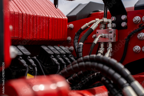 фотографія Hydraulic manifold valve block with connected high pressure hoses and steel tubing near red tractor counterweights
