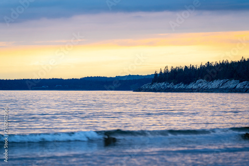 Quadro su tela New River Beach Provincial Park gentle ocean waves washing ashore along the forested coastline beneath a soft golden sunset glow over the Bay of Fundy, New Brunswick