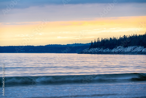 Quadro su tela New River Beach Provincial Park gentle ocean waves washing ashore along the forested coastline beneath a soft golden sunset glow over the Bay of Fundy, New Brunswick