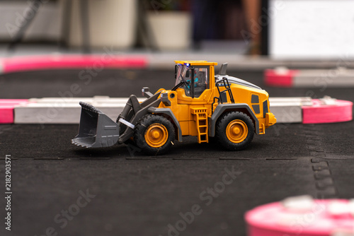 Obraz na płótnie Yellow scale model of a wheel loader with front bucket standing on a miniature track during demonstration