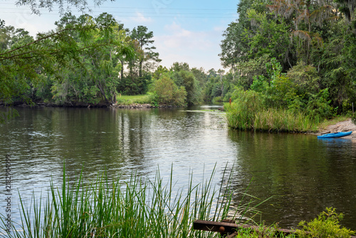 A blue kayak rests on the shore of the Waccamaw River near Riverfront Park and the Conway Riverwalk in Conway, South Carolina, in the Southeastern USA.