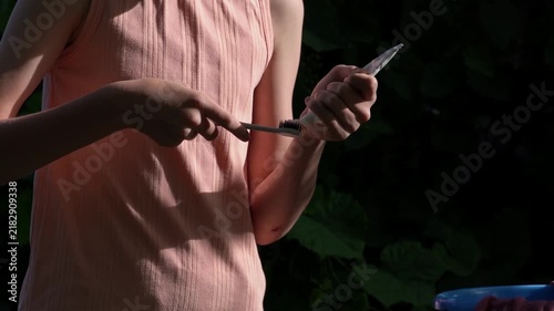 The girl squeezes toothpaste onto her toothbrush while carrying out her morning routine against the backdrop of nature during a hiking trip.