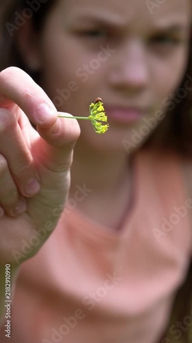 The teenage girl is watching a ladybug on the dill umbrella.