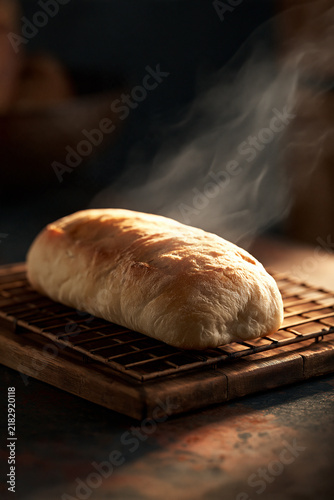 freshly baked ciabatta loaf with delicate steam, artisan ciabatta bread cooling on wooden rack, golden ciabatta loaf in a rustic artisan bakery