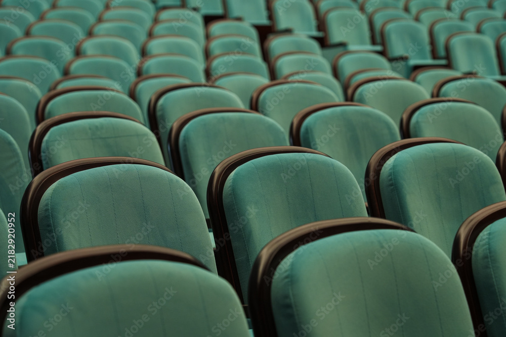 Obraz premium Empty turquoise theater chair awaiting audience