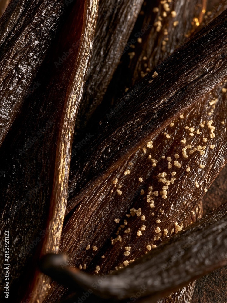 Fototapeta premium Close-up of a group of vanilla pods. the pods are dark brown in color and have a rough texture. they are arranged in a scattered manner, with some overlapping each other.