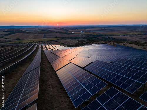 Solar panels at sunset in a rural area with the sun setting over distant hills and valleys