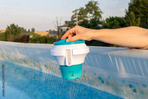 Фотография Person is using a floating chlorine dispenser with an integrated thermometer to